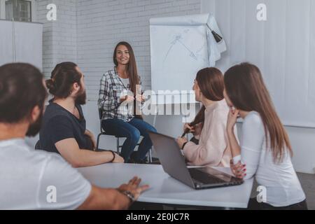 Giovane bella donna d'affari sorridente, leader riunione d'affari in ufficio. Gruppo di designer creativi che discutono delle startup sul posto di lavoro Foto Stock