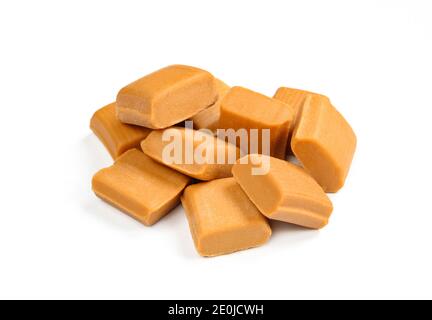 Mucchio di caramelle al caramello isolato su sfondo bianco. Gruppo di quadrati di caramelle malsane Foto Stock