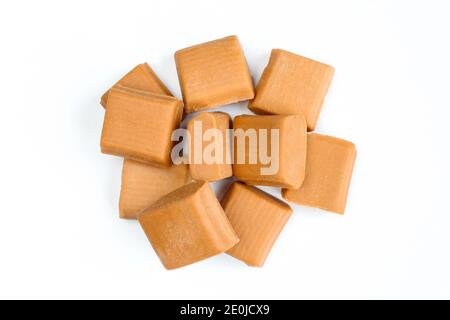 Mucchio di caramelle al caramello isolato su sfondo bianco. Gruppo di quadrati di caramelle malsane Foto Stock