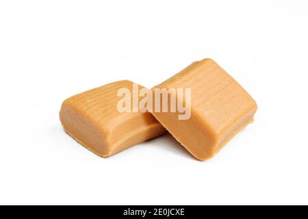 Due caramelle al caramello non confezionate isolate su sfondo bianco. Snack dolce e delizioso Foto Stock