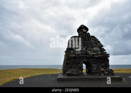 La grande struttura in pietra di Bárður Snæfellsás lungo la costa di Arnarstapi sulla penisola di Snaefellsnes in Islanda occidentale. Foto Stock