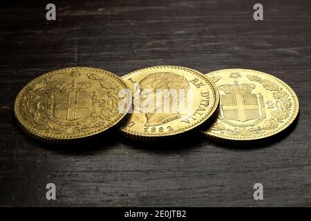 Monete d'oro italiane da 20 Lira su sfondo rustico in legno Foto Stock