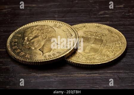 Monete d'oro italiane da 20 Lira su sfondo rustico in legno Foto Stock