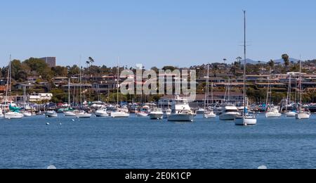 Barche ormeggiate nel porto di Newport Beach in California su un skyline della città di giorno soleggiato sullo sfondo Foto Stock