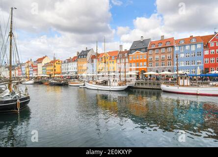 I turisti passeggiata, guida scheda barche e cenare presso caffetterie lungo la strada in una giornata autunnale del xvii secolo waterfront canal Nyhavn a Copenaghen, in Danimarca. Foto Stock