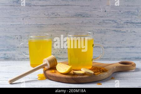 Bevanda tonica energetica con curcuma, zenzero, limone e miele su tavola di legno, fuoco selettivo Foto Stock