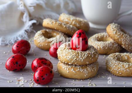 Biscotti tradizionali greci di Pasqua con semi di sesamo e uova colorate sul tavolo di legno, fuoco selettivo Foto Stock