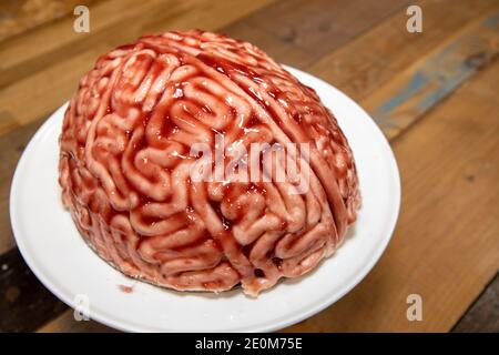 Una torta a forma di cervello con fragola fonte spazzolato su di esso per fare il pan di spugna guardare come un cervello sanguinoso umano reale per la parte di halloween Foto Stock