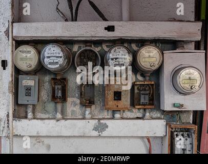 Contatori elettrici con apparecchiature arrugginite e cablaggio esposto su una parete esterna in Messico. Foto Stock