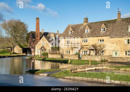 Fiume occhio alti livelli d'acqua nel villaggio di cotswold di macellazione inferiore la vigilia di Natale. Lower Slaughter, Cotswolds, Gloucestershire, Inghilterra Foto Stock