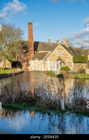 Fiume occhio alti livelli d'acqua nel villaggio di cotswold di macellazione inferiore la vigilia di Natale. Lower Slaughter, Cotswolds, Gloucestershire, Inghilterra Foto Stock