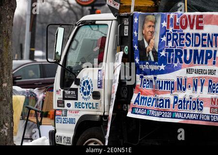 Molto tempo dopo che Donald Trump ha perso le elezioni del 2020, un sostenitore decora il suo camion con bandiere pro-Trump e anti-Biden e si siede a bordo strada in inverno Foto Stock