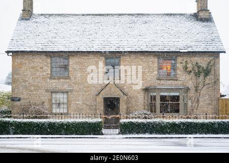 Cotswold casale in pietra sulla strada alta nella neve a natale. Shipton sotto Wychwood, Cotswolds, Oxfordshire, Inghilterra Foto Stock