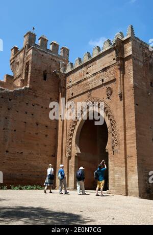 I turisti stranieri camminano attraverso l'entrata all'antica città romana di Chellah che si trova a sud di Rabat in Marocco. Foto Stock