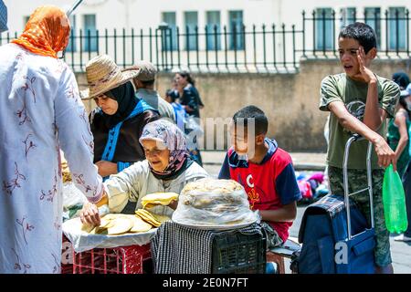 Una donna che vende pane piatto adiacente a Lahdim Square a Meknes. Meknes è una delle quattro città imperiali del Marocco. Foto Stock