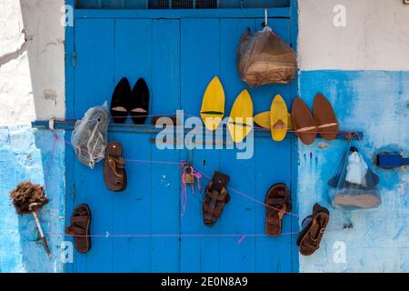 Vari set di scarpe appesi su una porta blu a Kasbah des Oudaias a Rabat in Marocco. Il sobborgo e' famoso per i suoi edifici blu e bianchi. Foto Stock