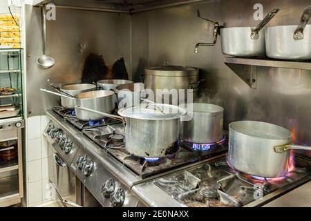 Varie pentole che cucinano su una stufa in una cucina industriale In Italia Foto Stock