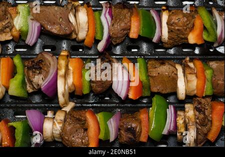 I kebab di carne e verdure cucinano orizzontalmente su una griglia calda come visto dall'alto. Foto Stock