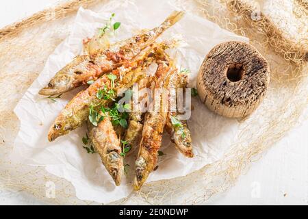 Il pesce caldo fritto puzzava di sale ed erbe su bianco carta Foto Stock