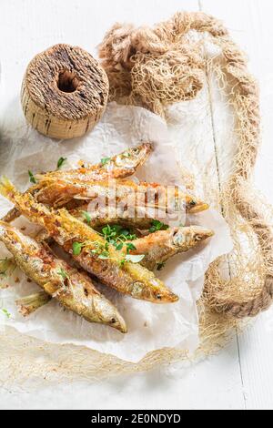 Pesce fritto odore e patatine con erbe e sale sopra tavola bianca Foto Stock