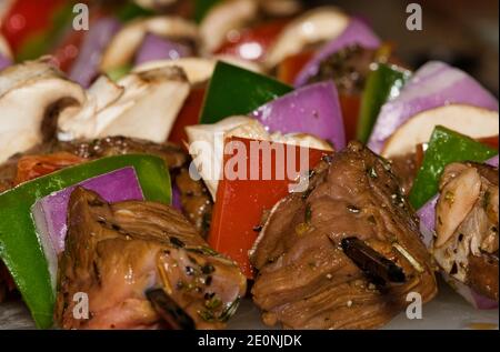 Kebab di manzo e verdure che cucinano su una griglia per barbecue, angolo di messa a fuoco selettivo con punte di spiedo. Foto Stock