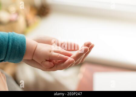 La madre usa la sua mano per tenere la mano minuscola del suo bambino per fargli sentire il suo amore, caldo e sicuro.amore di famiglia Foto Stock