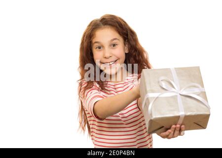 Felice giovane bella ragazza sorridente gioiosamente tenendo fuori il regalo di Natale alla telecamera isolata su bianco copyspace regalo festivo infanzia Foto Stock