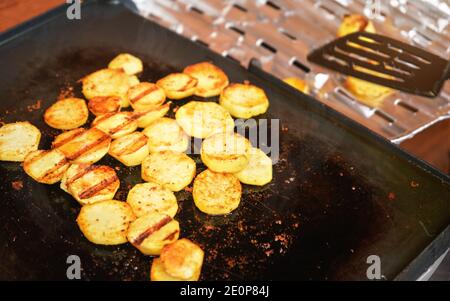 Patate tagliate a piccoli cerchi, condite con spezie, grigliate sulla griglia elettrica Foto Stock