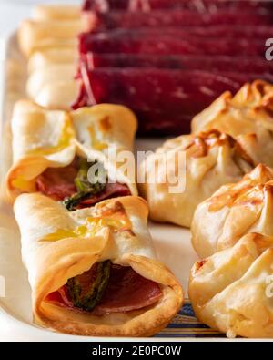 Piano verticale per il menu del ristorante. Cecina de León e involtini di prosciutto con asparagi selvatici. Messa a fuoco selezionata con sfondo bianco e luce laterale. Foto Stock