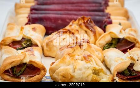 Vista macro orizzontale di sacchetti ripieni di formaggio, involtini di prosciutto e burritos messicani con prosciutto e asparagi selvatici con sfondo fuori fuoco Foto Stock