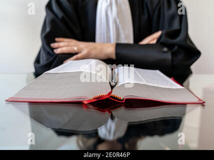 Giustizia, avvocato donna che tiene e legge libro aperto di legge rossa - diritto francese Foto Stock