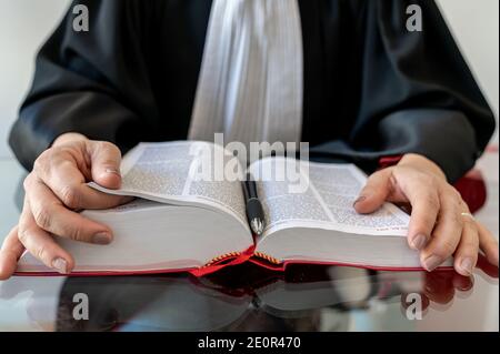 Giustizia, avvocato donna che tiene e legge libro aperto di legge rossa - diritto francese Foto Stock