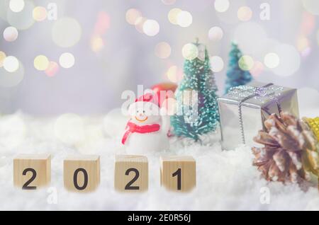 Felice anno nuovo 2021 idee creative a cubetti su neve e sfondo pupazzo di neve e albero di Natale. Foto Stock