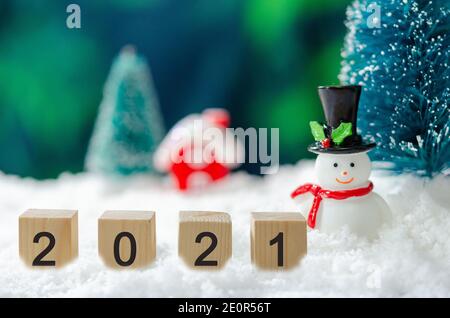 Felice anno nuovo 2021 idee creative a cubetti su neve e sfondo pupazzo di neve e albero di Natale. Foto Stock