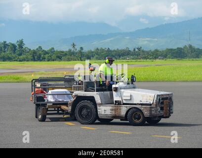 Il gestore di bagagli attende un volo per arrivare all'aeroporto di Nadzab in Lae, la capitale della provincia di Morobe e la seconda città più grande di Papua Nuova Guine Foto Stock