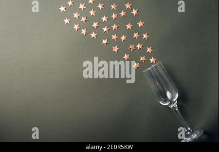 Una bella foto di un bicchiere con alcune stelle che ne escono su un tavolo di colore scuro. Foto Stock