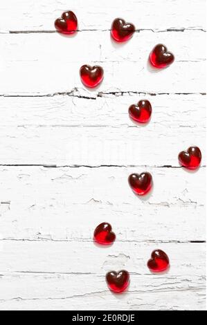Cuori di vetro rosso su sfondo bianco di legno. Concetto di vacanza. Foto Stock