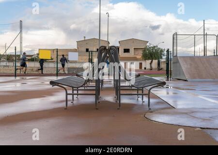 Panchine in metallo all'interno di una sala sportiva con persone irriconoscibili che corrono sullo sfondo Foto Stock