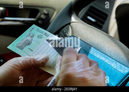 Scrittura su controllo in bianco a con in auto con guanti al momento del deposito di stimoli governativi, controllare con i guanti per la sicurezza messa a fuoco morbida Foto Stock