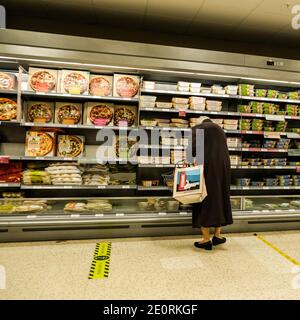 Londra UK, gennaio 02 2021, anziani Senior Woman Shopping da solo a Waitrose guardando pasti pronti e pizze Foto Stock