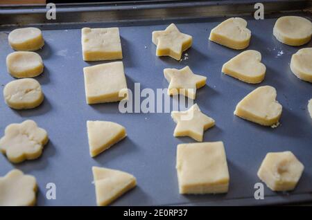 Biscotti shortbread tagliati in forme diverse e disposti ordinatamente su una pecora da forno pronta a cucinare nel over. Foto Stock