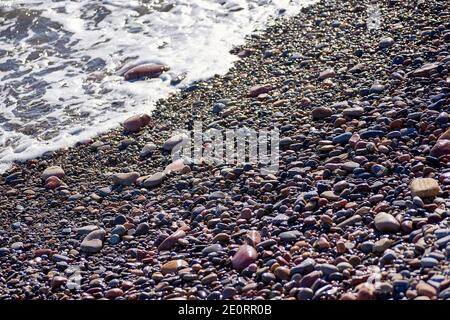 Piccole rocce spiaggia, sfondo non focalizzato, nessuno, in primo piano, soleggiato, grandi e piccole pietre Foto Stock