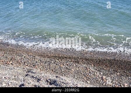 Piccole rocce spiaggia, sfondo non focalizzato, nessuno, in primo piano, soleggiato, grandi e piccole pietre Foto Stock