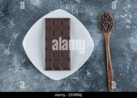 Bar di cioccolato con gocce di cioccolato su sfondo marmoreo Foto Stock