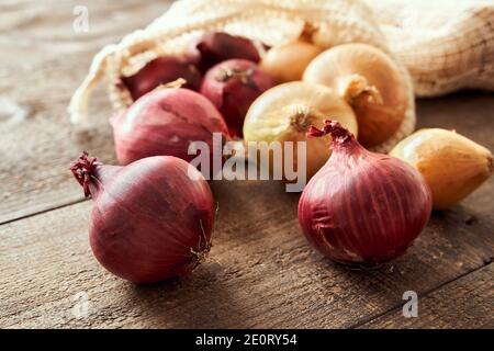 Cipolle viola e gialle su un tavolo, con una borsa ecologica riutilizzabile in cotone biologico Foto Stock