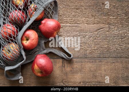 Mele rosse in una borsa a corda su un tavolo di legno, vista dall'alto con spazio per la copia Foto Stock