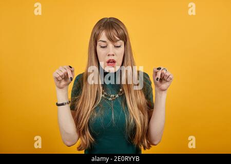 Bei punti giovani impressionanti con le dita di indice giù. Scioccato stupito posando sfondo isolato, ritratto in studio. Persone emozioni sincere concetto di stile di vita. Spazio di copia. Guardando. Espressione positiva Foto Stock