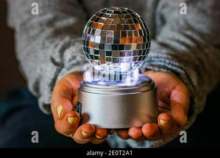 Una donna che tiene una palla da discoteca brillante Foto Stock