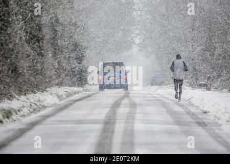 Kidderminster, Regno Unito. 2 gennaio 2021. Tempo del Regno Unito: Con temperature diurne che non riescono ad aumentare molto al di sopra del gelo in Worcestshire e strade già ghiacciate, Kidderminster è colpito da pesanti docce di neve mattina rendendo le condizioni di guida pericolose per tutti gli automobilisti. Una figura maschile solitaria può essere visto in inverno, isolato da dietro nelle piste da neve di un veicolo precedente. Credit: Lee Hudson/Alamy Live News Foto Stock