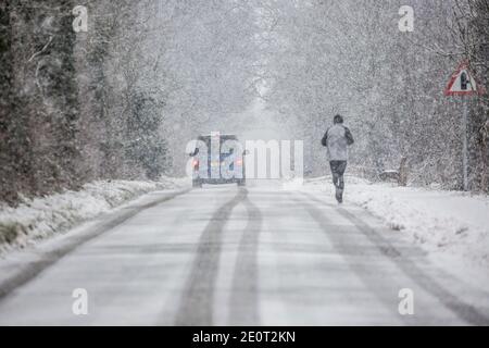 Kidderminster, Regno Unito. 2 gennaio 2021. Tempo del Regno Unito: Con temperature diurne che non riescono ad aumentare molto al di sopra del gelo in Worcestshire e strade già ghiacciate, Kidderminster è colpito da pesanti docce di neve mattina rendendo le condizioni di guida pericolose per tutti gli automobilisti. Una figura maschile solitaria può essere visto in inverno, isolato da dietro nelle piste da neve di un veicolo precedente. Credit: Lee Hudson/Alamy Live News Foto Stock